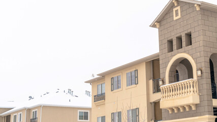Panorama Apartment exterior with balconies and snowy roofs against cloudy sky in winter