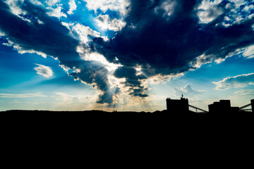 Cloudy sky above silhouette of factory