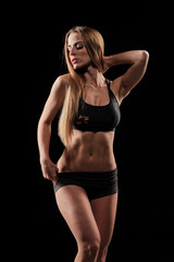 Fototapeta na wymiar Sexy skinny blonde fitness girl wearing sport clothes with long hair standing up while looking down in a sexy way showing her silhouette