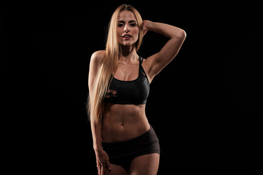 Sexy skinny blonde fitness girl wearing sport clothes with long hair standing up while looking at camera in a sexy way showing her silhouette