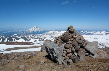 Stone pyramid on the slope of Gorely volcano. Vilyuchinsky volcano is visible on the background, Kamchatka Peninsula, Far East Russia