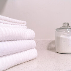 Square Folded white towels and glass jar with white powder on the bathroom countertop