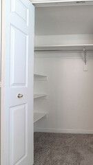 Vertical Walk in closet with double hinged doors plain white wall and gray floor carpet