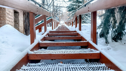 Panorama crop Focus on grate metal treads of outdoor stairs against snowy hill in winter