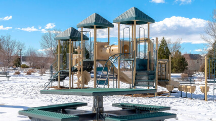 Panorama Playground and picnic table at a snow covered park on a sunny winter day