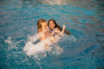 Mother and daughter are resting on the sea. Mother and her daughter are swimming in the pool, playing and laughing. A mother holds her daughter in her arms in an open-air pool in Thailand. Cute girl s