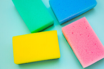 Colorful sponges for washing dishes on green background. Artificial fiber not eco-friendly tool. Things for kitchen.