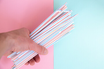 Man holding plastic straws for cocktails. Pastel pink and blue colors. Summer vibes. Hipster party...