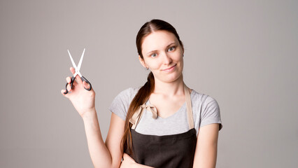 Hairdresser holding scissors at gray studio background