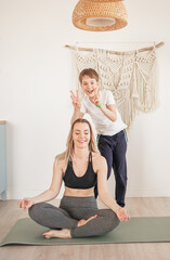 Fototapeta na wymiar Mom does yoga at home, and her son has fun and bothers her.