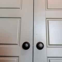 Square crop Bedroom interior with shiny double wooden door and matte black round knobs