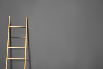 Modern wooden ladder on grey background. Space for text