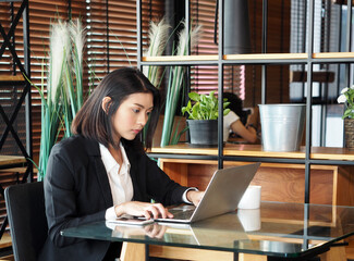 Woman in suit sitting with notebook computer.