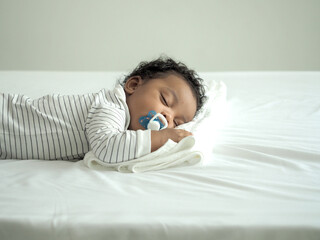 African baby boy is sleeping. Baby sucks pacifier.