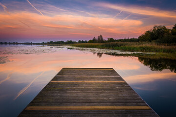 wooden bridge over lake at sunset