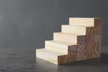 Steps made with wooden blocks on table against grey background, space for text. Career ladder