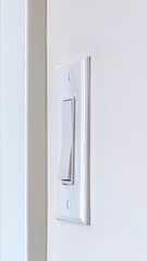 Vertical Side view of electrical rocker light switch mounted on white interior wall