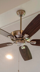 Vertical Electrical fan with built in lights installed on decorative wooden ceiling beam