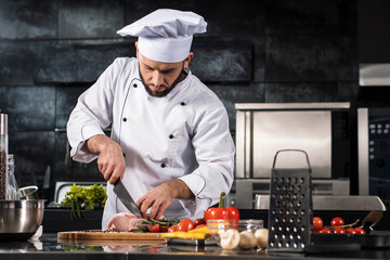 Chef cutting meat at kitchen. Chef in uniform cut beef at planked.