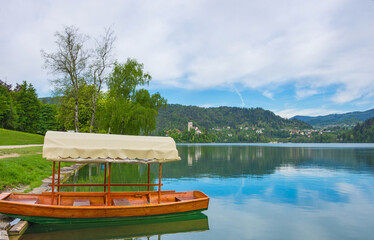 Traditional Pletna boat waiting for tourists on Lake Bled, with the lake island and charming little church in the background, famous tourists attraction in Slovenia