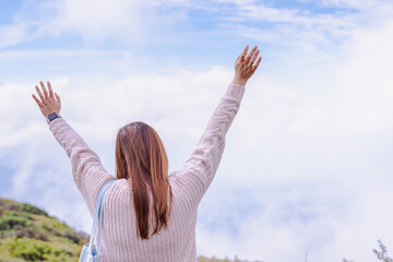 solo asian woman traveler open arms and embracing nature from top of mountain in spring season