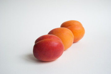 Close-up of three ripe apricots lined