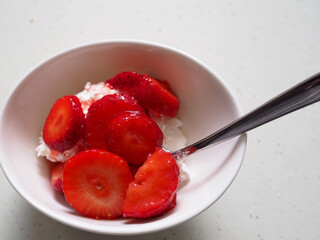 Cuenco blanco con fresas con nata visto desde arriba.