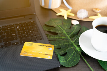 A credit card is placed on the computer and has a cup of coffee next to the top view.