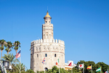 Fototapeta na wymiar La Torre de Oro (Tower of Gold) with some flags. Seville, Andalusia, Spain.