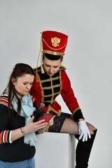 beautiful girl in an old hussar costume and in black boots and with a gun and a girl with a phone
