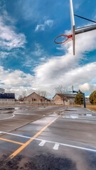 Vertical Basketball courts on neighborhood park with houses and playground in background