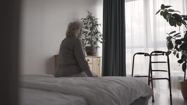 Abandoned senior female crying in nursing home room, suffering helplessness