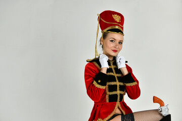 beautiful girl in an old hussar costume and in black boots and with a gun