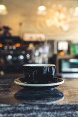 closeup black cup of hot coffee in cafe with soft-focus and over light in the background