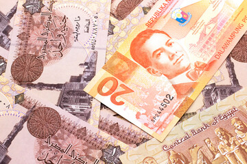 An orange twenty piso bank note from the Philippines with Egyptian one pound bank notes close up in macro
