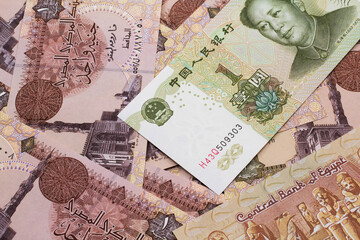 A close up image of a green, one Chinese yuan bank note, close up on a background of brown Egyptian one pound bank notes.  Shot in macro