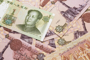 A close up image of a green, one Chinese yuan bank note, close up on a background of brown Egyptian one pound bank notes.  Shot in macro