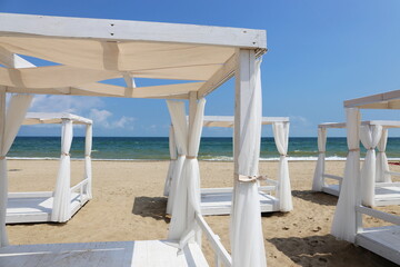 Fototapeta premium white canopy beach beds by the sea on a white sand beach in summer
