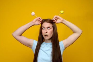 young european woman playes with cake pops on yellow background