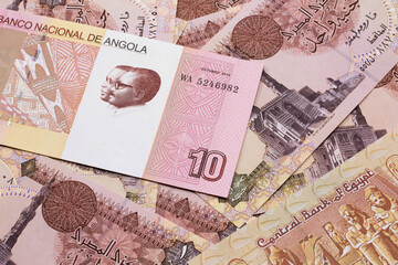 An red and white ten Angolan kwanza bank note on a background of Egyptian one pound bank notes
