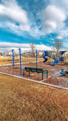 Vertical frame Childrens playground with neighborhood homes background under cloudy blue sky