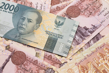 A grey, two thousand Indonesian rupiah bank note with Egyptian one pound bank notes close up in macro