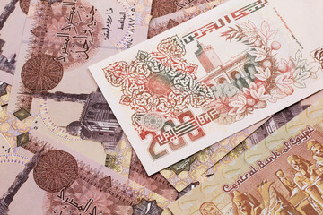 A macro image of a beige two hundred Algerian dinar bank note on a background of Egyptian one pound bank notes