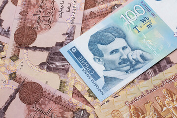 A close up of a blue and white, one hundred Serbian dinar bank note on a background of Egyptian one pound bank notes