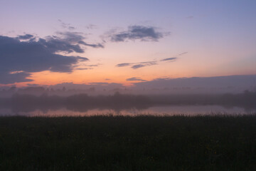 Purple sunset over a small river and reflection of the sky in the water.