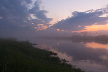 Purple sunset over a small river and reflection of the sky in the water.