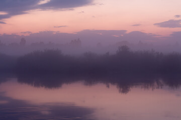 Obraz premium Purple sunset over a small river and reflection of the sky in the water.