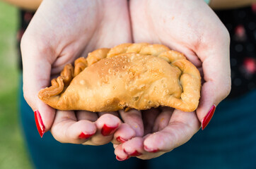 Young woman eating traditional fried Spanish and Argentine empanadas at a street food market