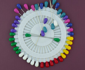 Some various colored brooches pin placed on top of a set of brooches pin