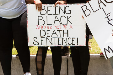 African American Woman Holding a "Being Black Should Not Be A Death Sentence" Sign
